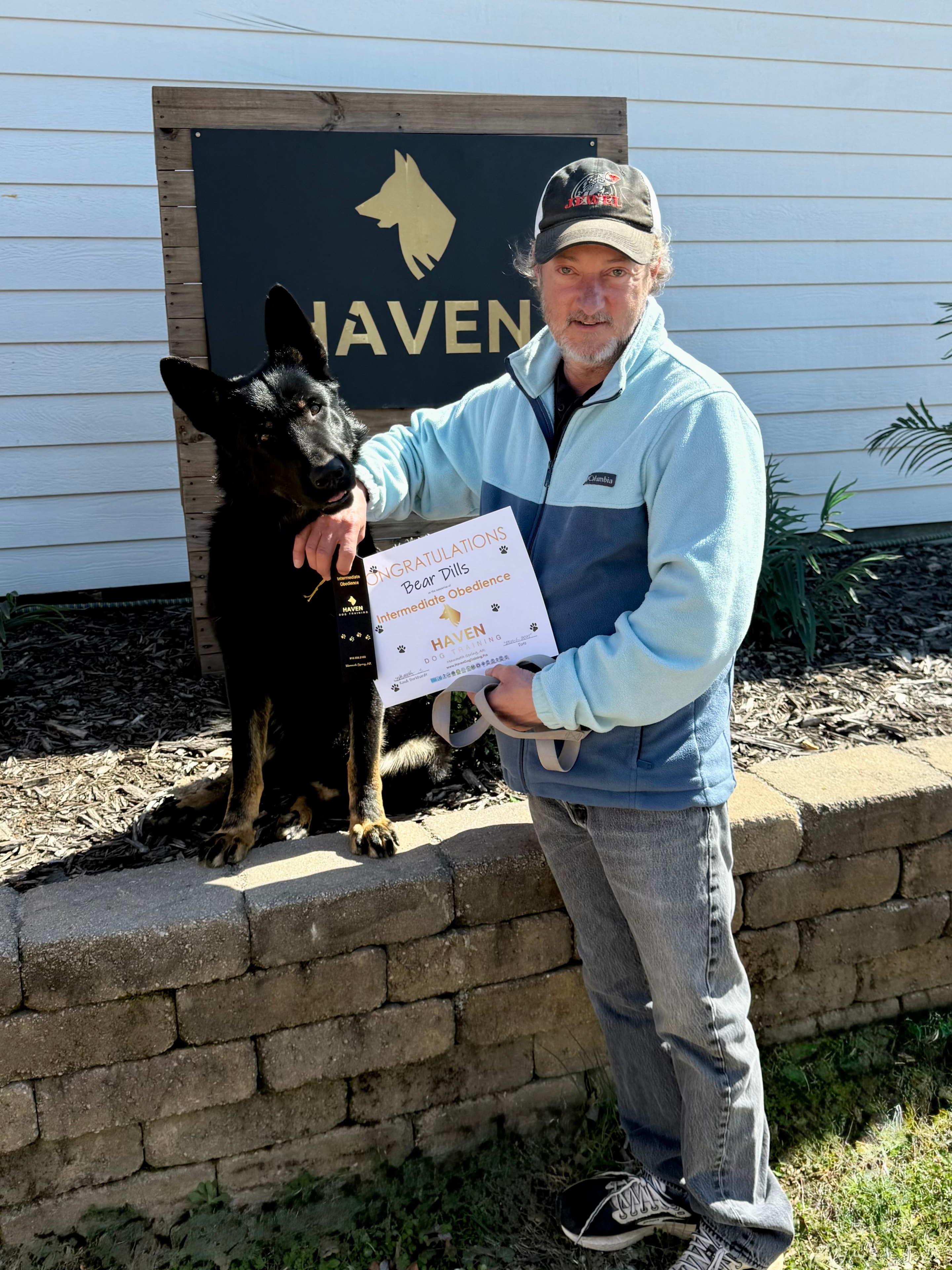 Bear Dills — Intermediate Obedience graduate with owner at Haven sign