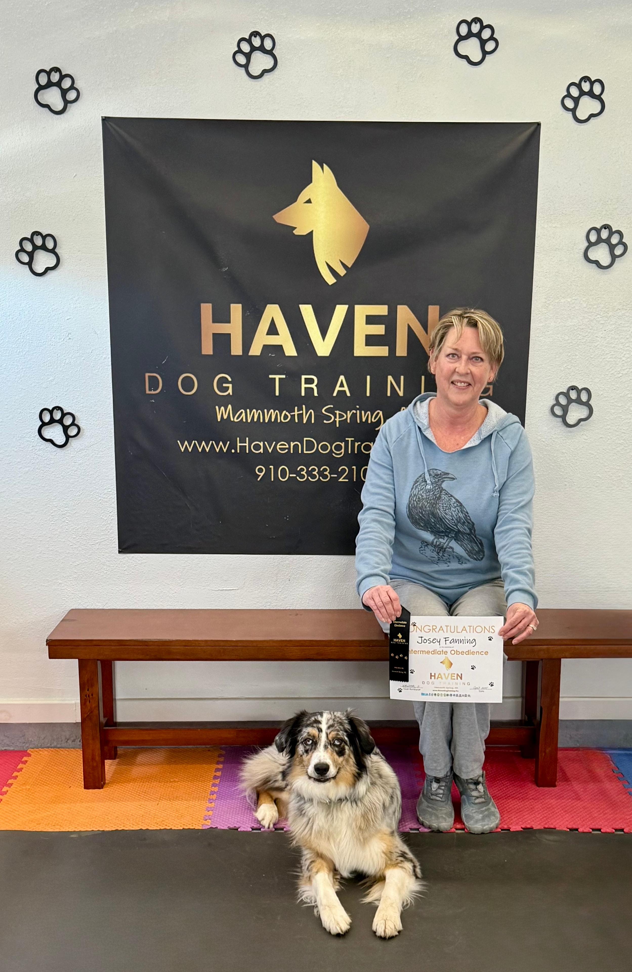 Josey Fanning — woman holding Intermediate Obedience certificate with Australian Shepherd at Haven banner