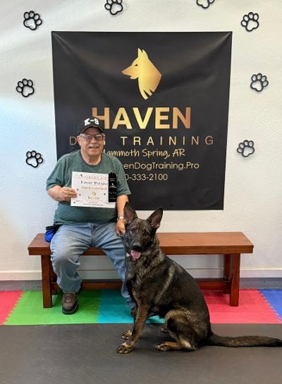 Kimber — handler holding graduation certificate with German Shepherd at Haven banner