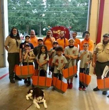 Scout troop group photo with dog at fire station holding orange gear bags