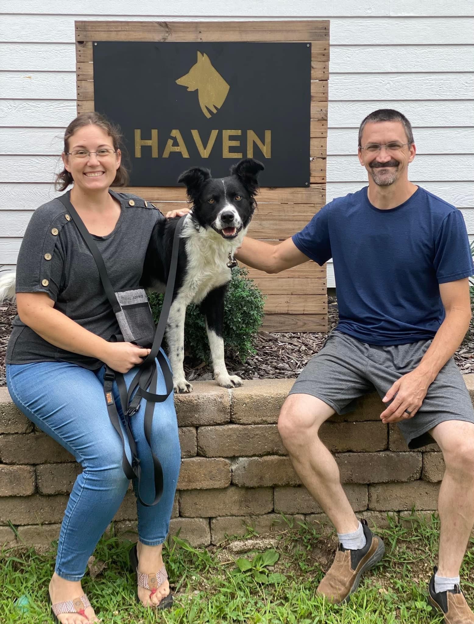 Couple with Border Collie posing in front of Haven Dog Training sign