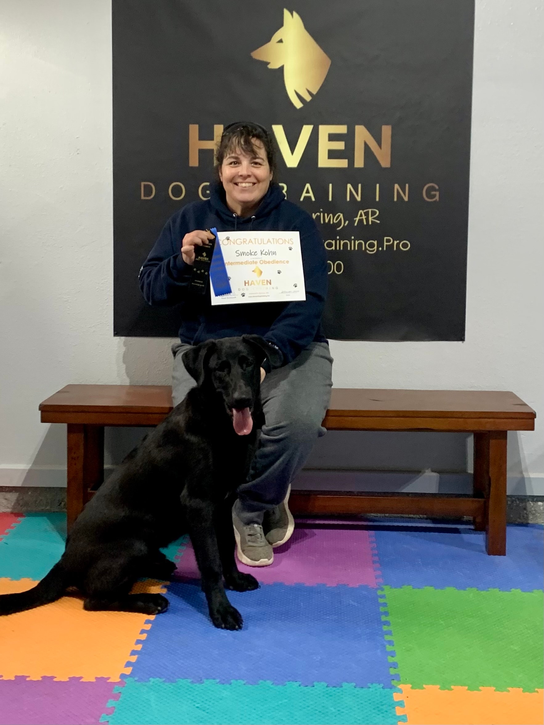 Smoke Kohn — Intermediate Obedience graduate with owner and black Lab at Haven banner