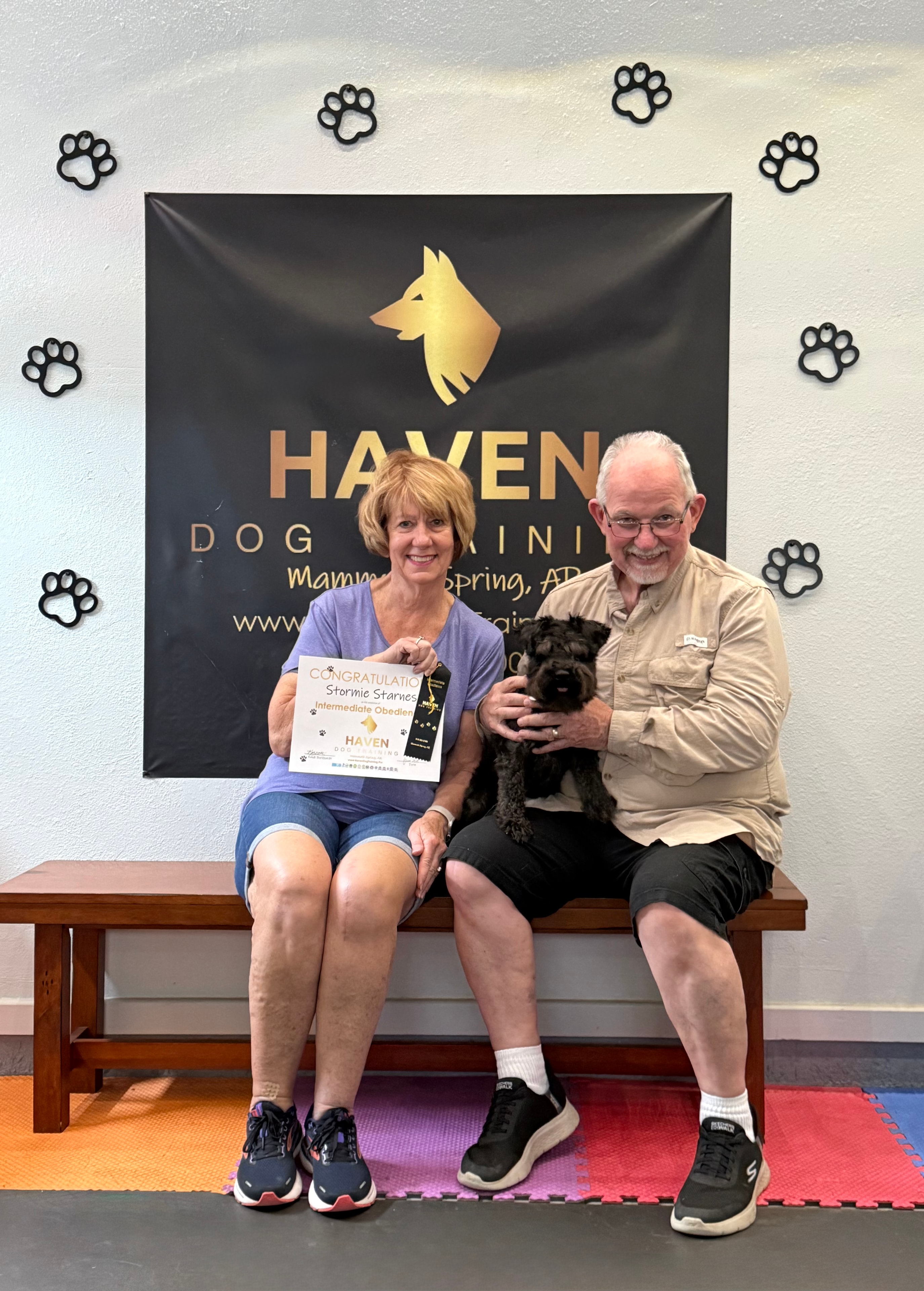 Stormie Starnes — couple with black Schnauzer holding Intermediate Obedience certificate at Haven banner