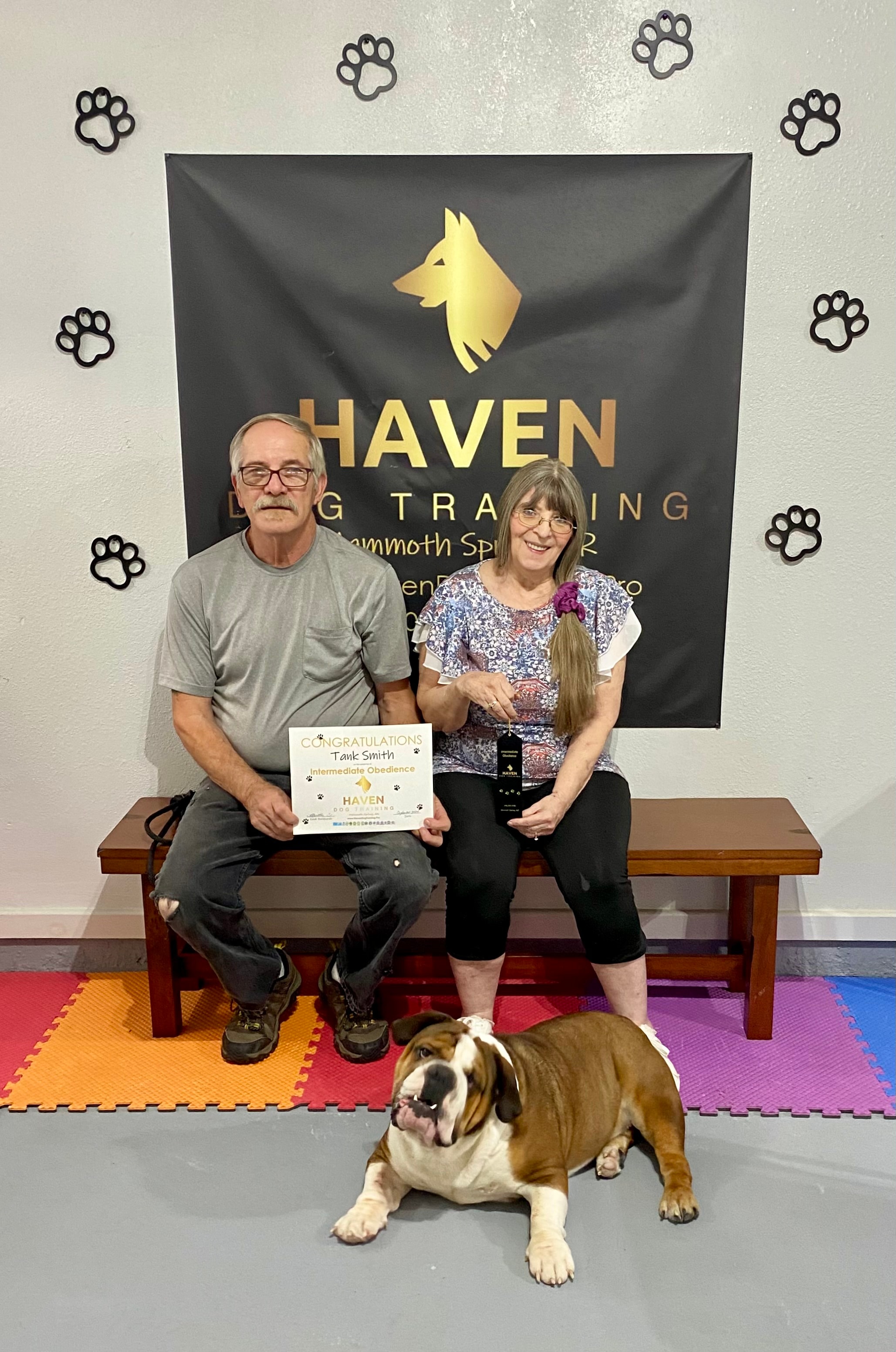Tank Smith — couple with English Bulldog holding Intermediate Obedience certificate at Haven banner