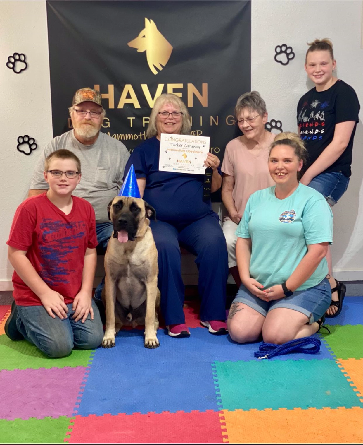 Tucker Caraway — family celebrating Intermediate Obedience graduation with large dog in party hat