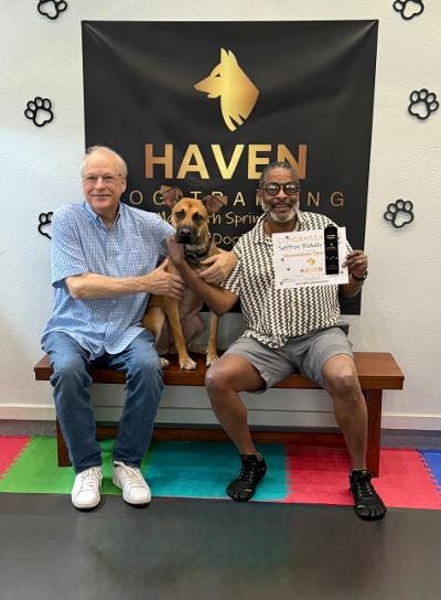 Two men posing with a dog during training session at Haven