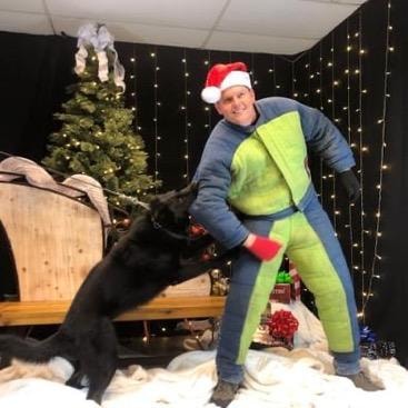 Trainer in Santa hat playing with black dog at Christmas event